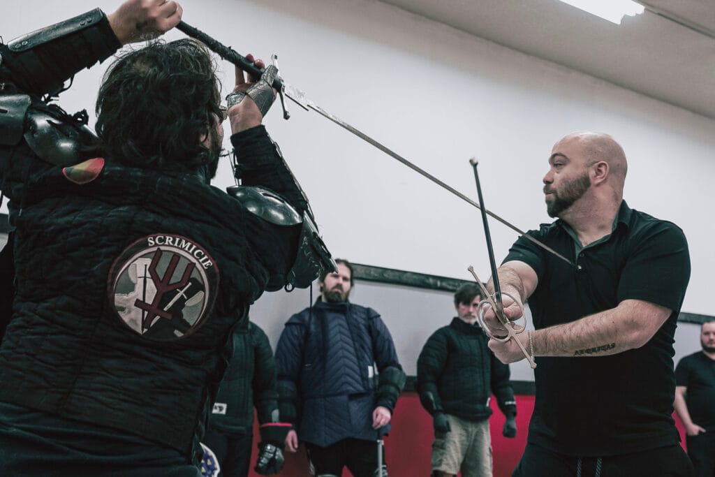 Deux instructeurs de l'Académie Scrimicie démontrent une technique de combat à l'épée longue en métal durant un cours d'escrime ancienne.